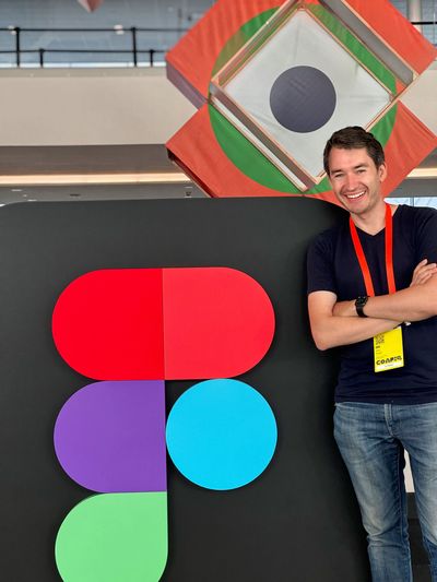 Leo Vogel smiling next to a large Figma logo installation at Config, Figma's annual design conference